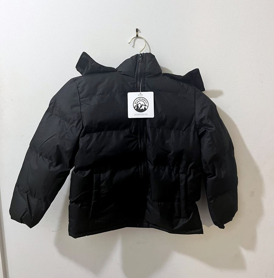 A new black children’s puffer coat with a hood, on a hanger with its tag attached