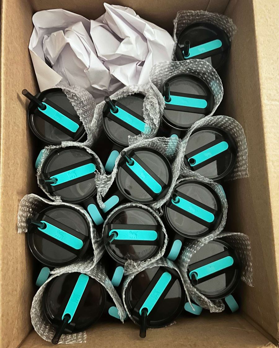 An open cardboard box packed with new black Stanley tumblers, lids up, each wrapped in bubble wrap